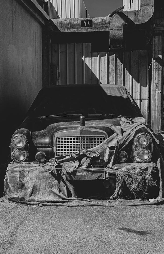pexels photo 11257203 A black and white photo of a vintage abandoned car in an industrial setting.